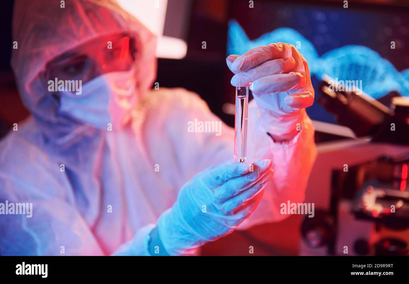 Nurse in mask and white uniform, holding tube with liquid and sitting ...