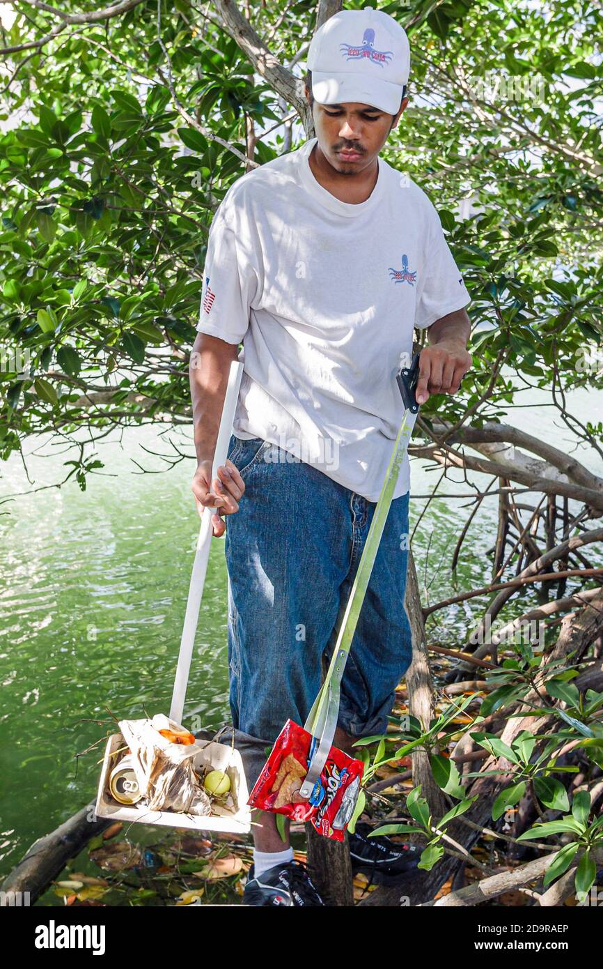 Miami Beach Florida,teen teens teenagers Job Corps volunteer volunteers,Black African boy filling garbage bag,clean up cleaning Tatum Waterway trash l Stock Photo
