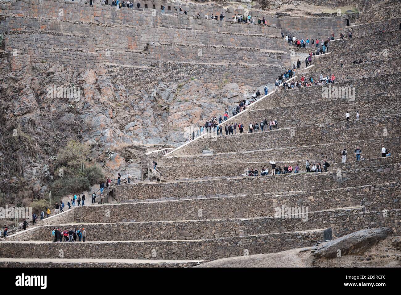Tourists dwarfed by the scale of the Terraces of Pumatallis at the Incan ruins at Ollantaytambo, Peru Stock Photo