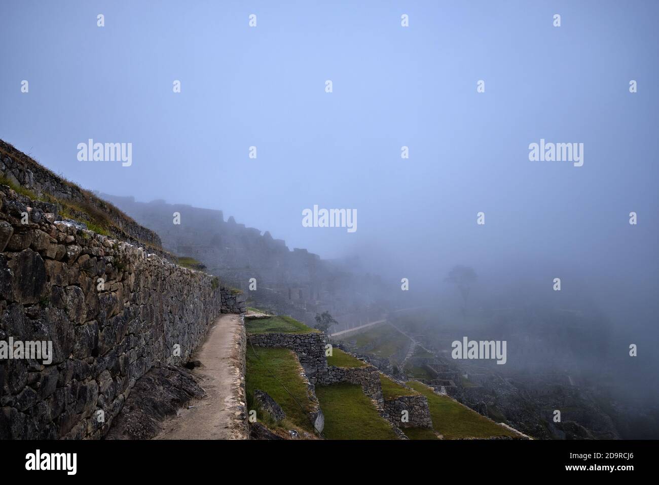 Mist and low cloud roll in over the terraces before sunrise dawn at the ruins of Machu Picchu, Peru Stock Photo