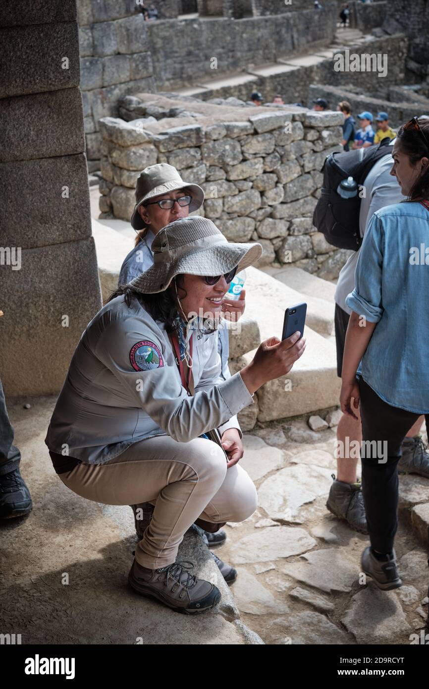 Woman in sunhat takes a photo photograph picture in the ruins at Machu Picchu, Peru Stock Photo