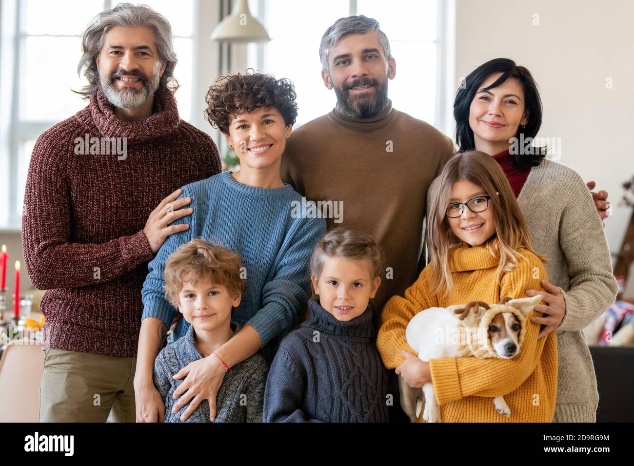Young large happy family of three generations and cute pet gathered for dinner Stock Photo