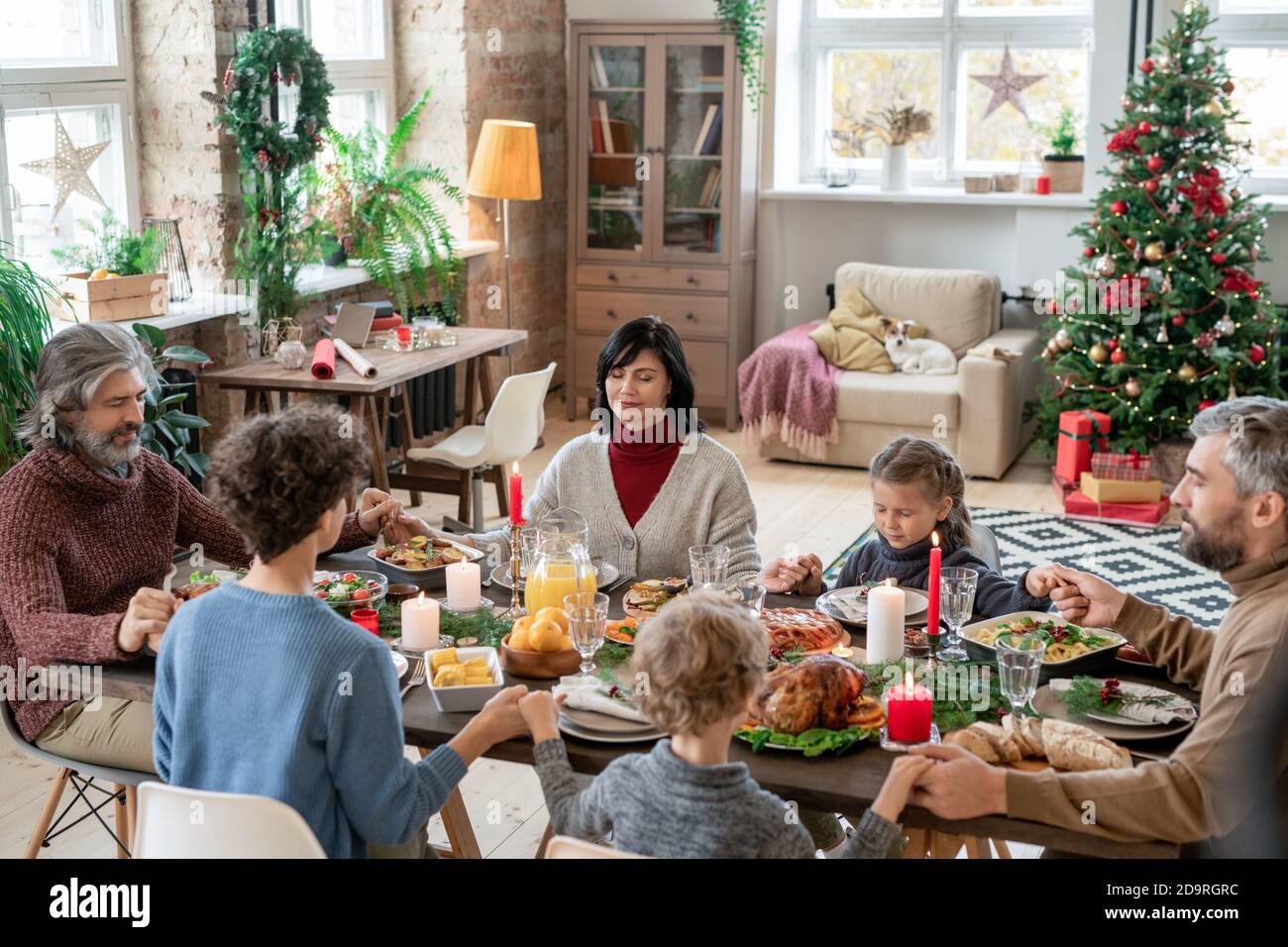 Large family consisting of three generations praying by served festive table Stock Photo