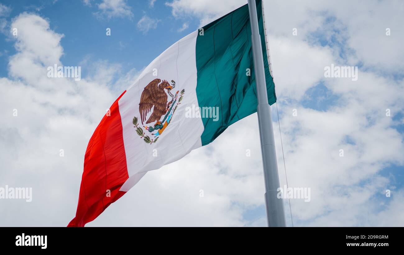Mexican Flag Waving in the Wind Under a Blue Sky Stock Photo