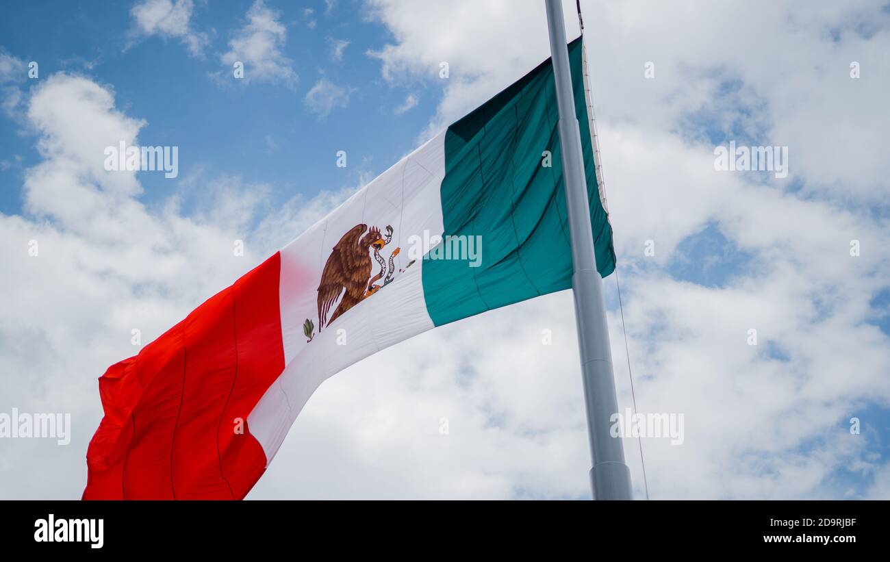 Mexican Flag Waving in the Wind and Slightly Cloudy Sky Stock Photo
