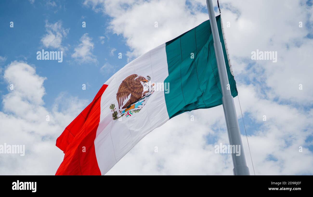 Mexican Flag Waving in the Wind and Blue Cloudy Sky as the Background Stock Photo