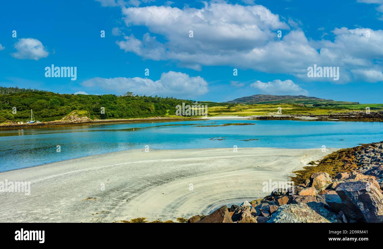 Isle of Eigg, Small Isles, Hebrides, Scotland.  A beautiful bay at low tide with silver sands, blue sea, blue sky and white fluffy clouds. Landscape, Stock Photo