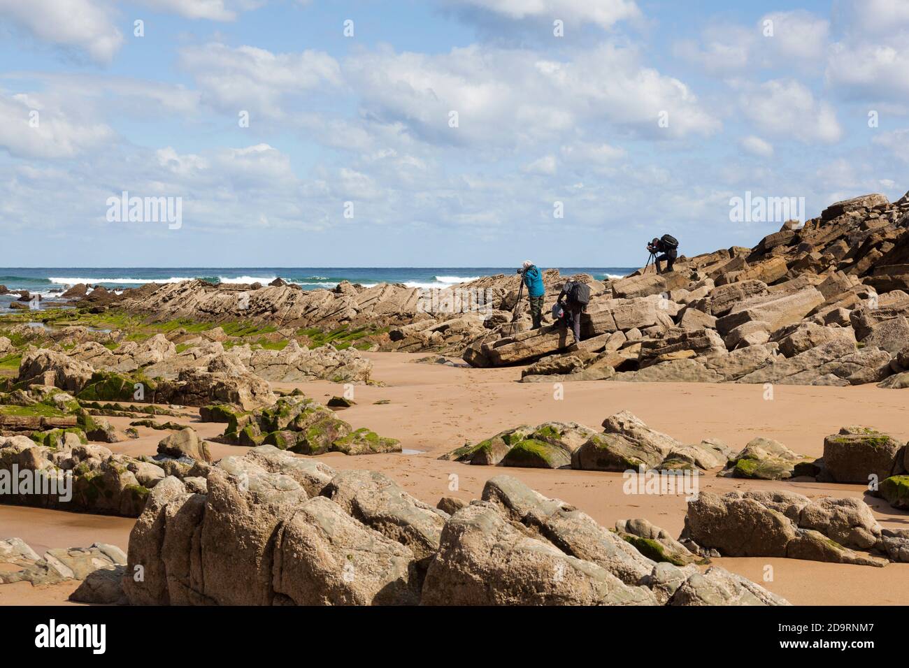 Three photographers taking pictures at a rocky beach Stock Photo