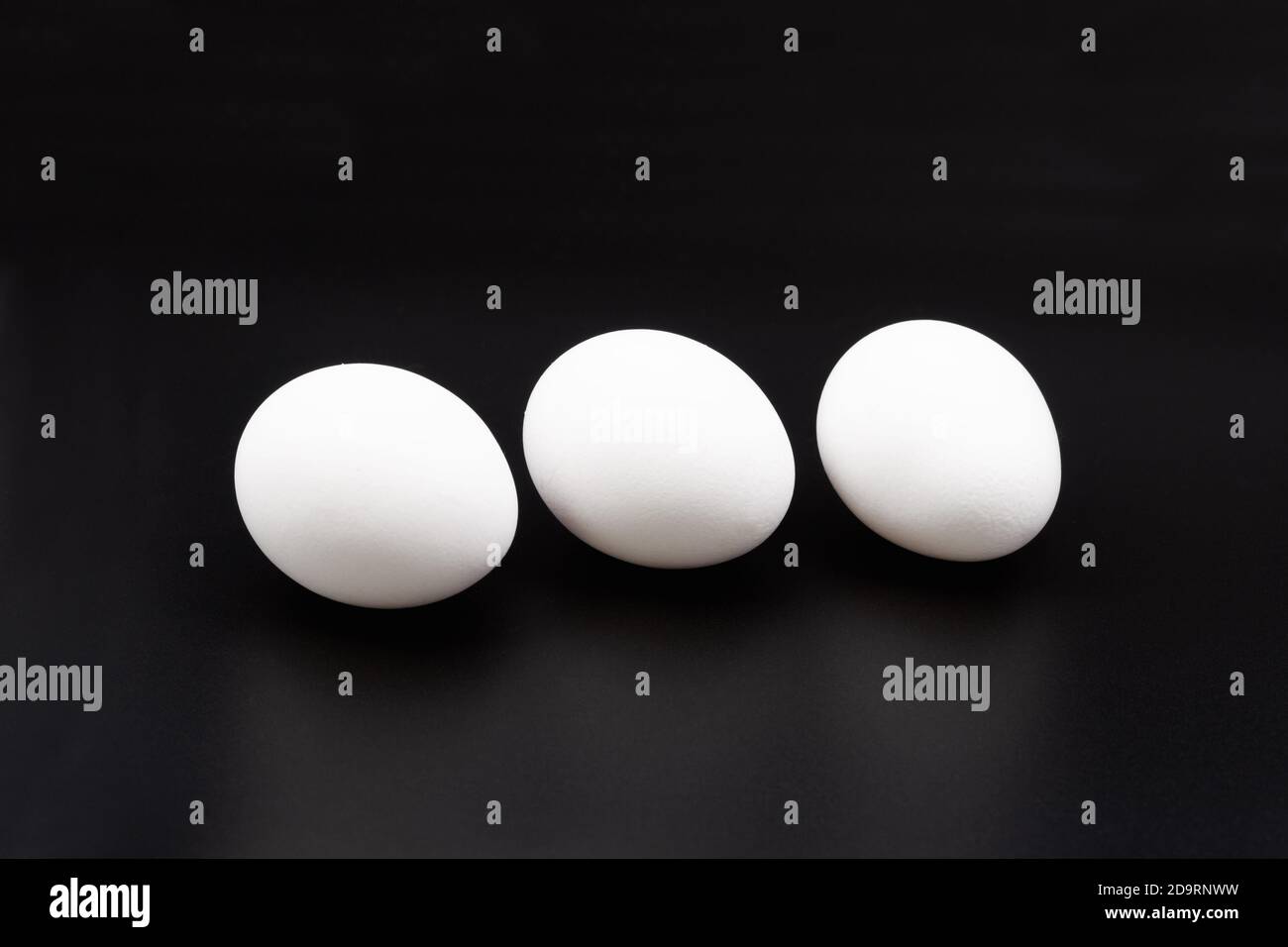 White chicken eggs. Close-up. On a black background. Stock Photo