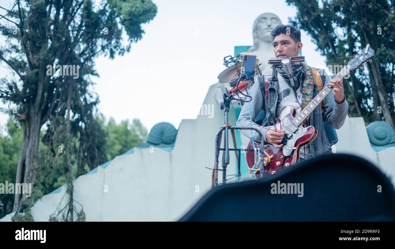 Man Playing Several Instruments at Once Performs in Front of a Fountain
