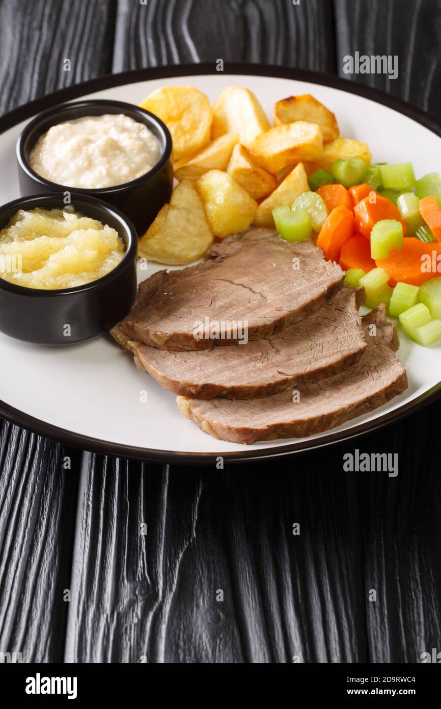 Tafelspitz is boiled beef in broth, served with a vegetables and horseradish close-up in a plate on the table. vertical Stock Photo
