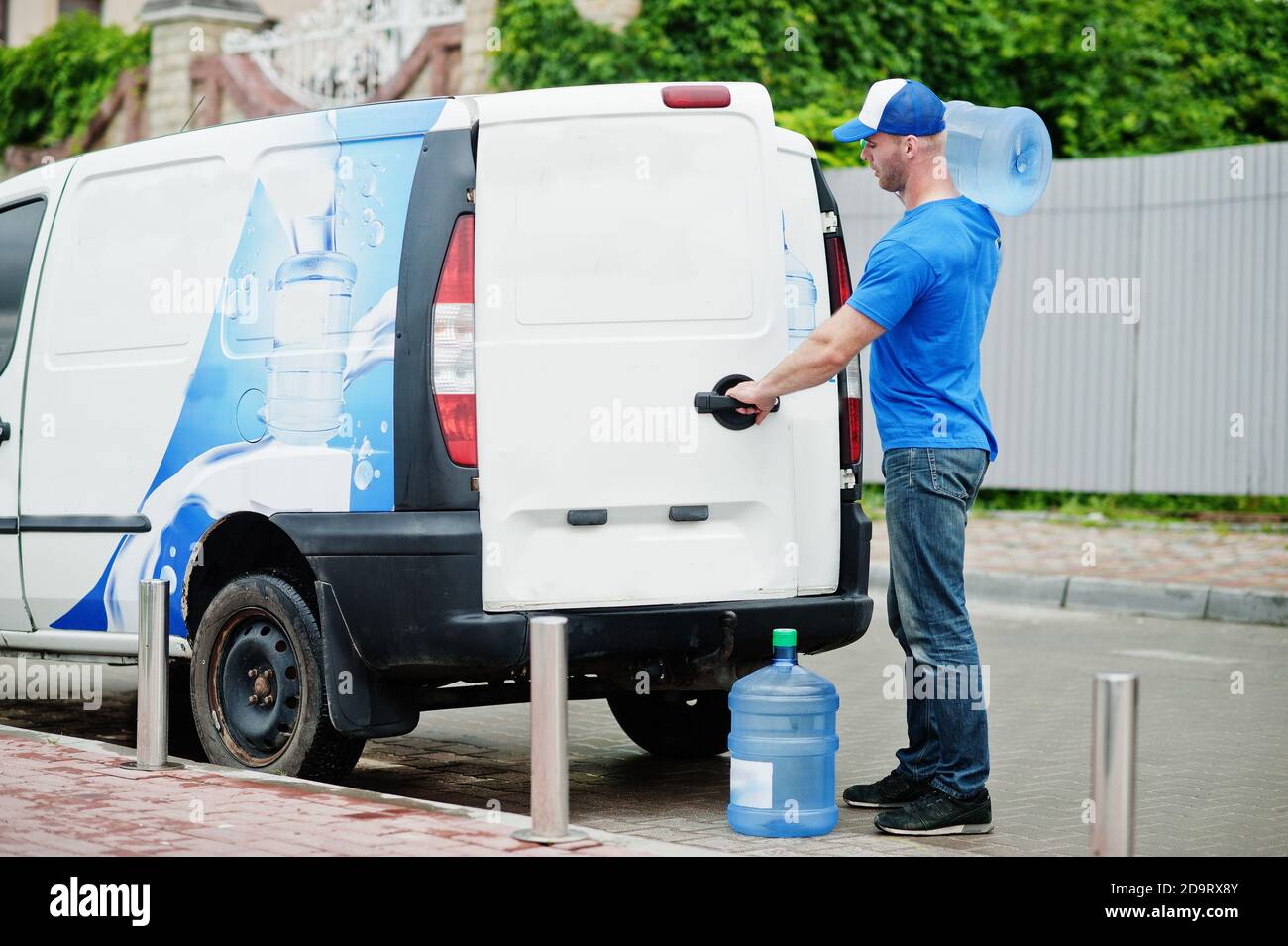 Delivery man in front cargo van delivering bottles of water Stock Photo