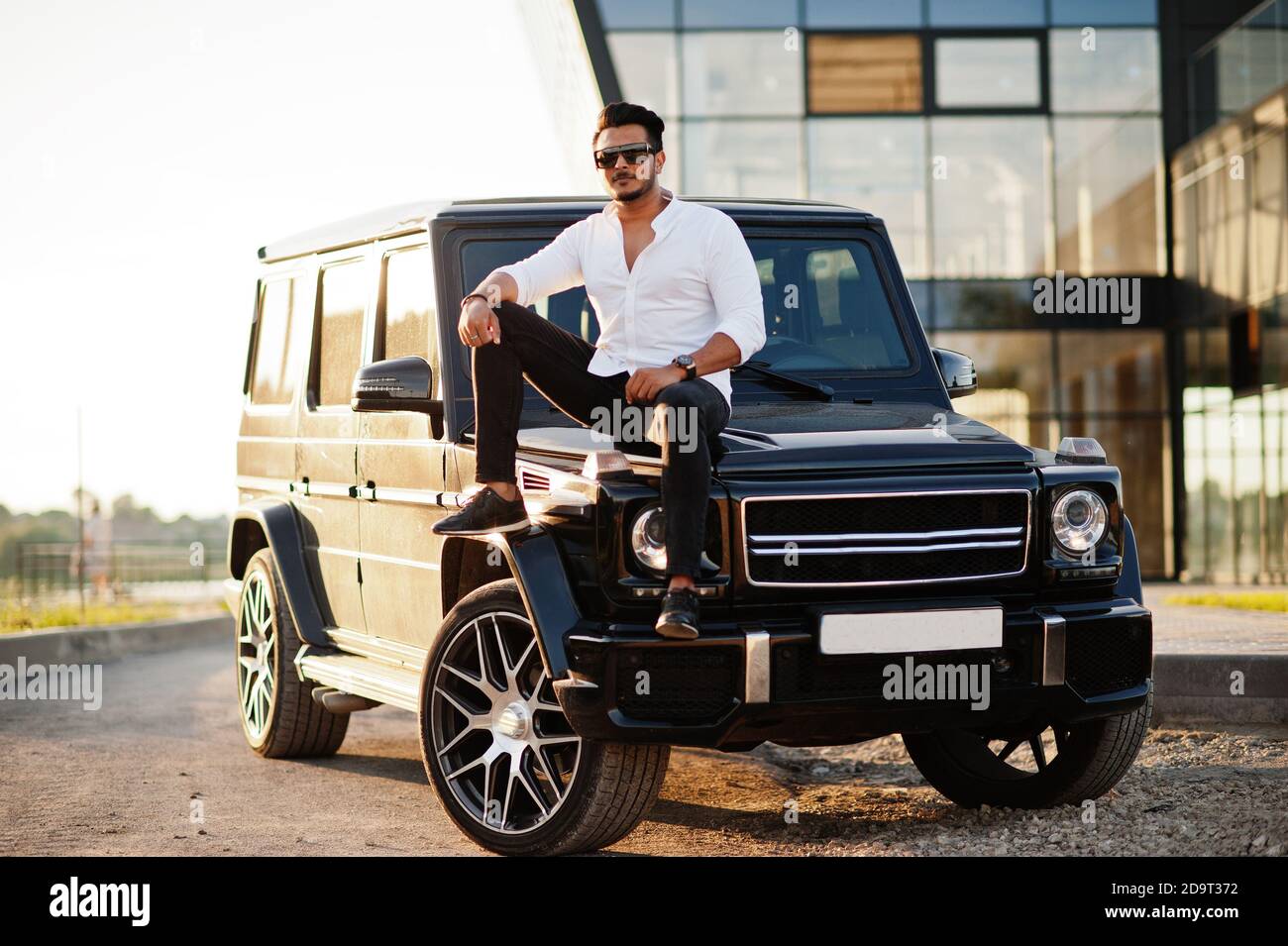 Solid asian man in white shirt and sunglasses posed near black mafia suv car.  10459281 Stock Photo at Vecteezy