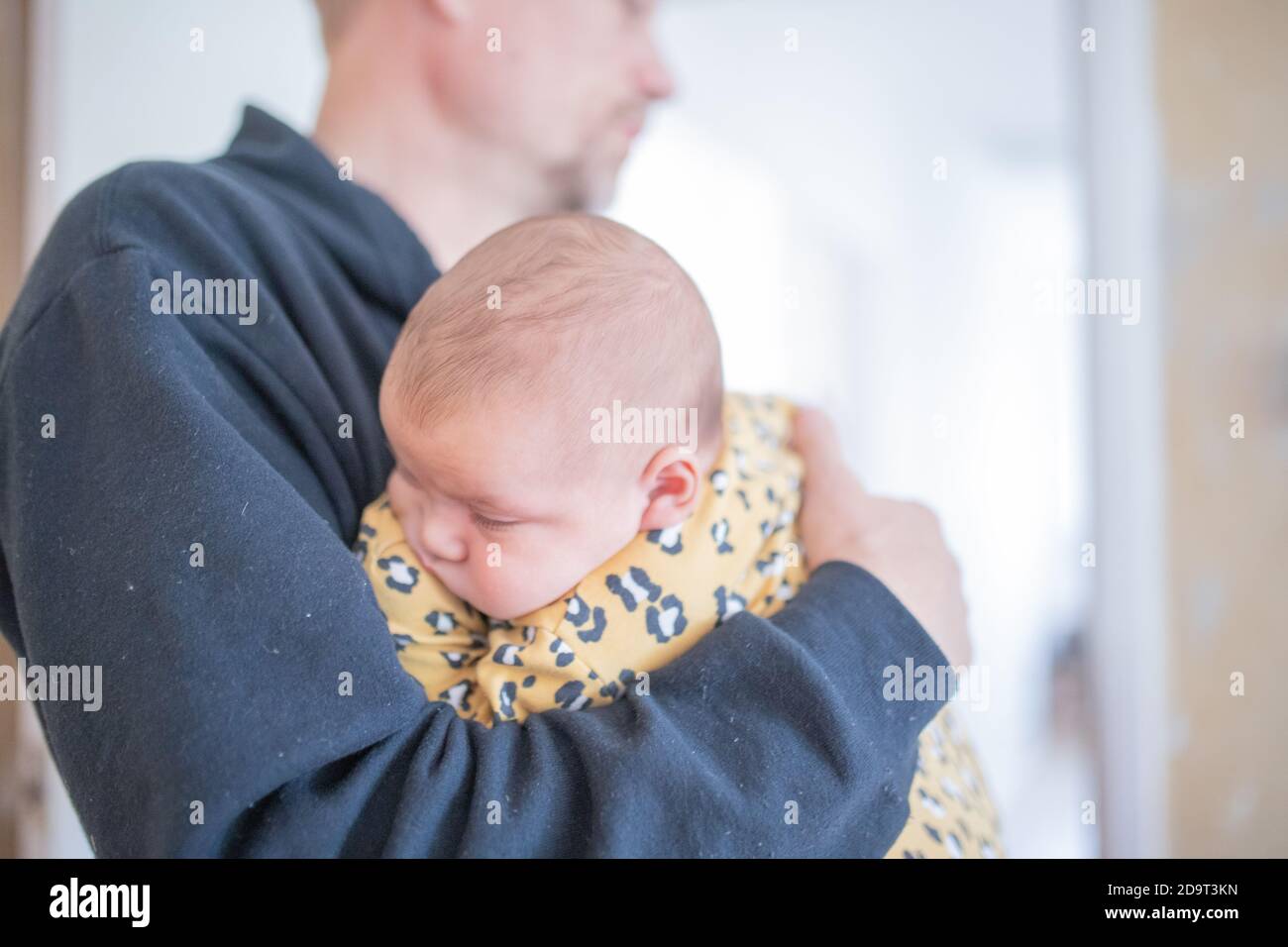 Sleeping Baby Girl Wearing a Yellow Onesie in the Arms of Her Granddad