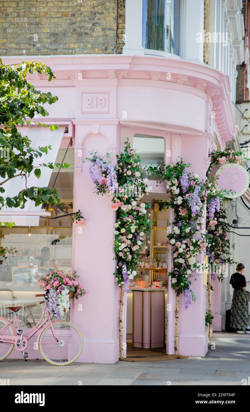 Portrait View of a Pink Cake Shop Entrance with Flowers and a Bicycle