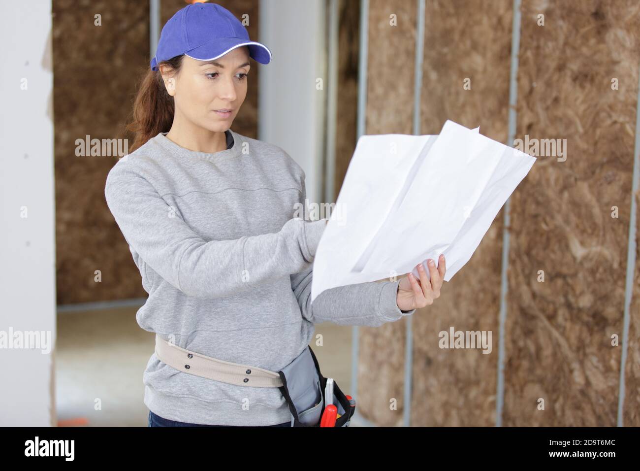 woman in builder helmet looking at blueprint Stock Photo - Alamy
