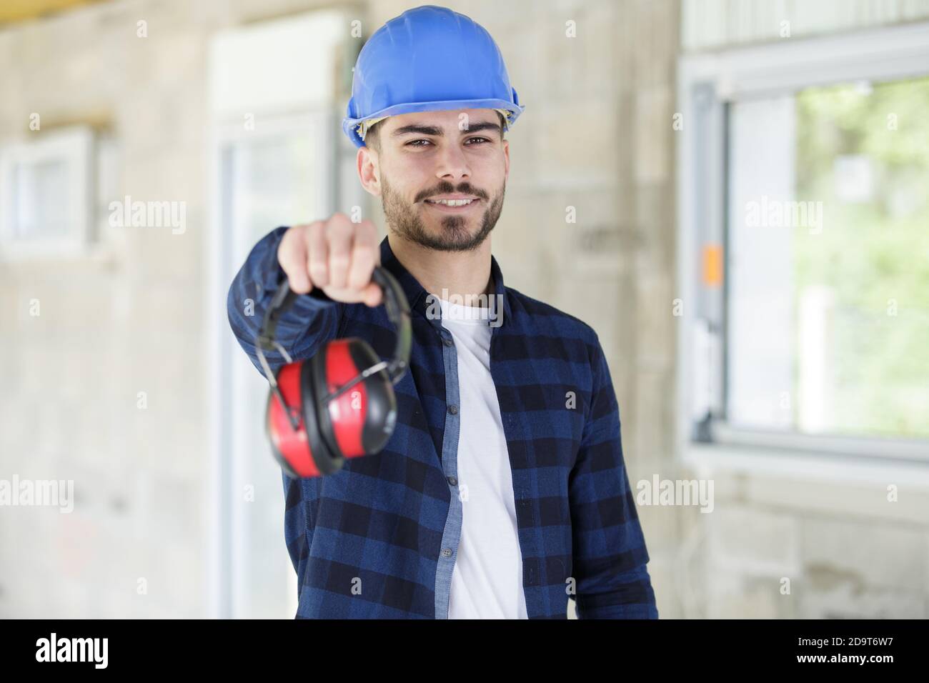 young male worker offering earmuffs Stock Photo