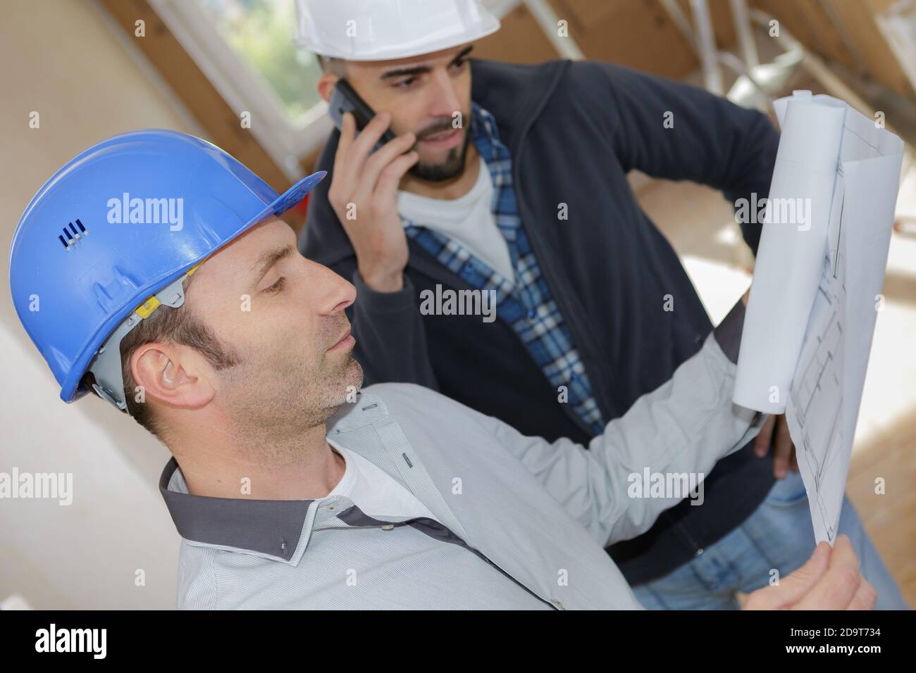 male engineers using mobile phone at construction site Stock Photo