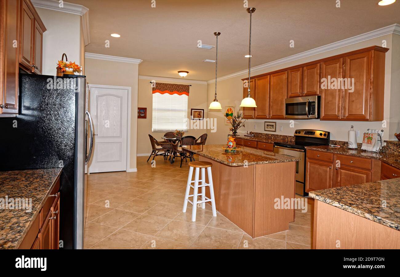 large modern kitchen; granite counters; center island; wood cabinets;  ceramic tile floor, set on diagonal, round table; chairs; recessed  lighting; han Stock Photo - Alamy