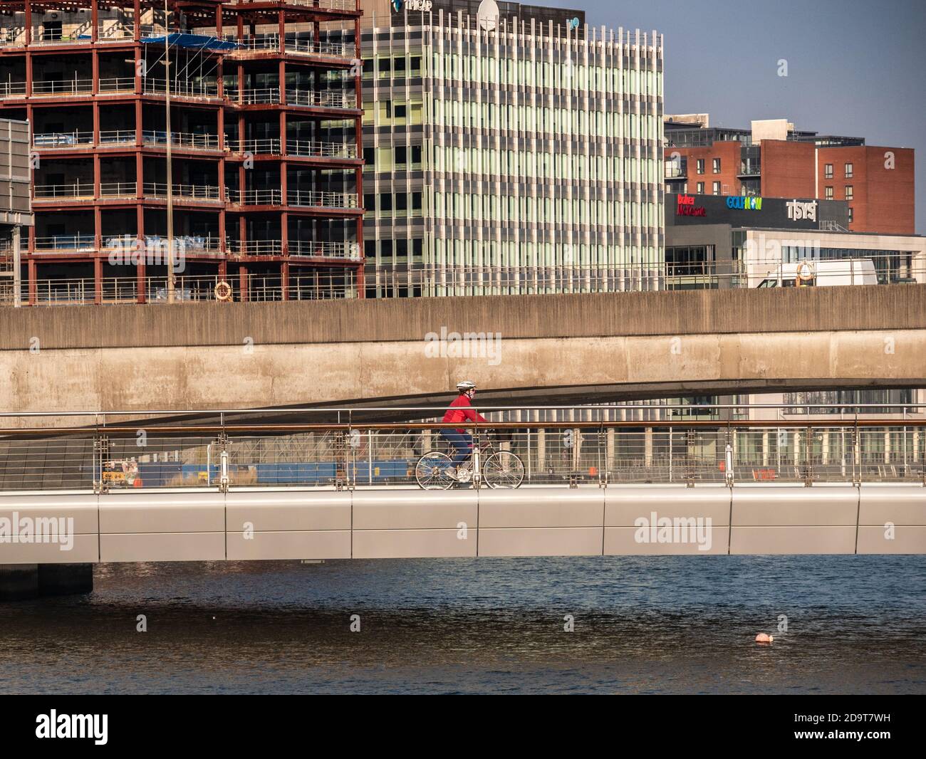 Belfast, Northern Ireland, UK, 7 November 2020: A cyclist crosses the Lagan Weir Bridge on a bright sunny morning. Cycling is growing in popularity in the city during the Coronavirus pandemic Stock Photo
