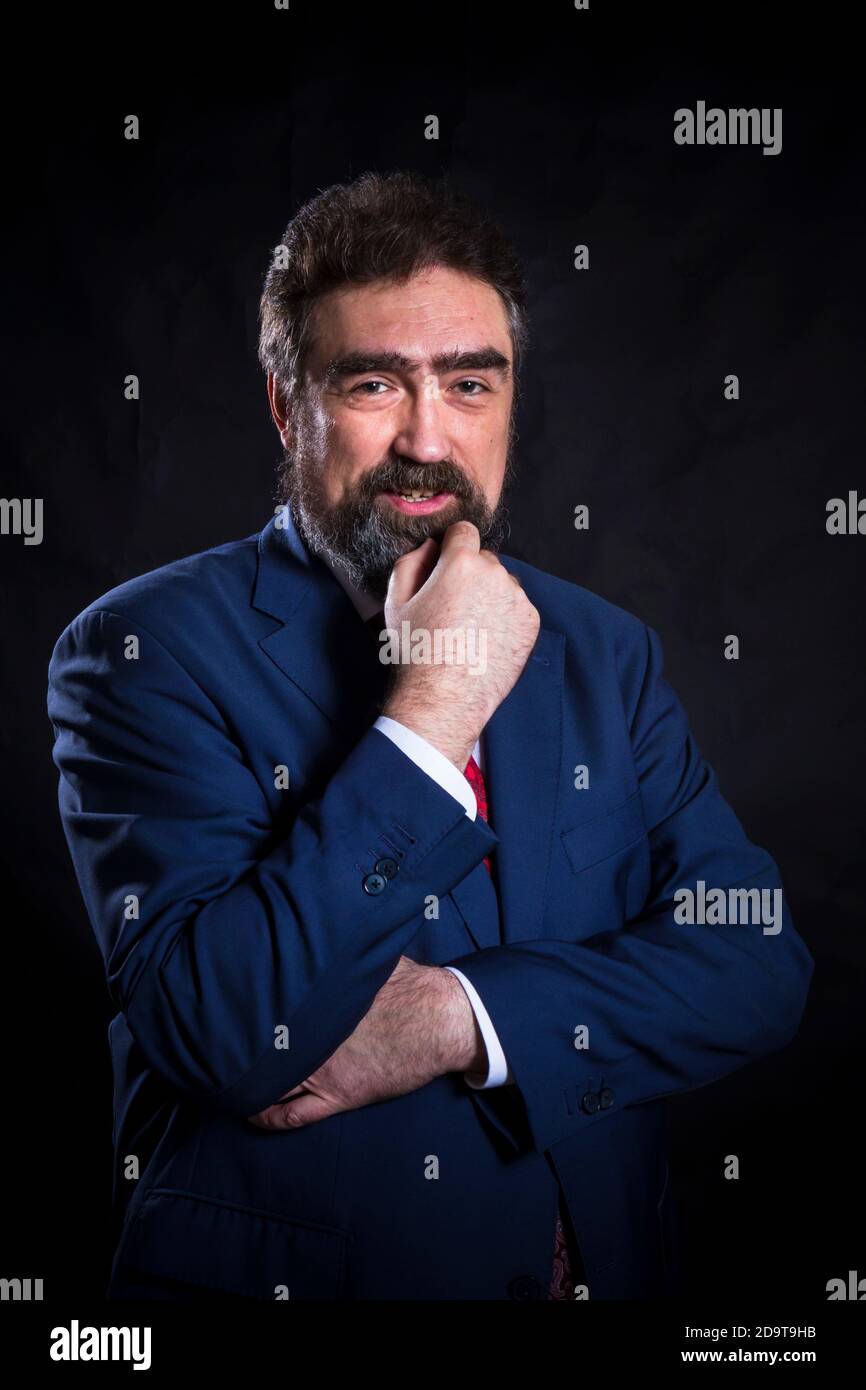 Mature businessman dressed in blue suit with red tie studio portrait ...