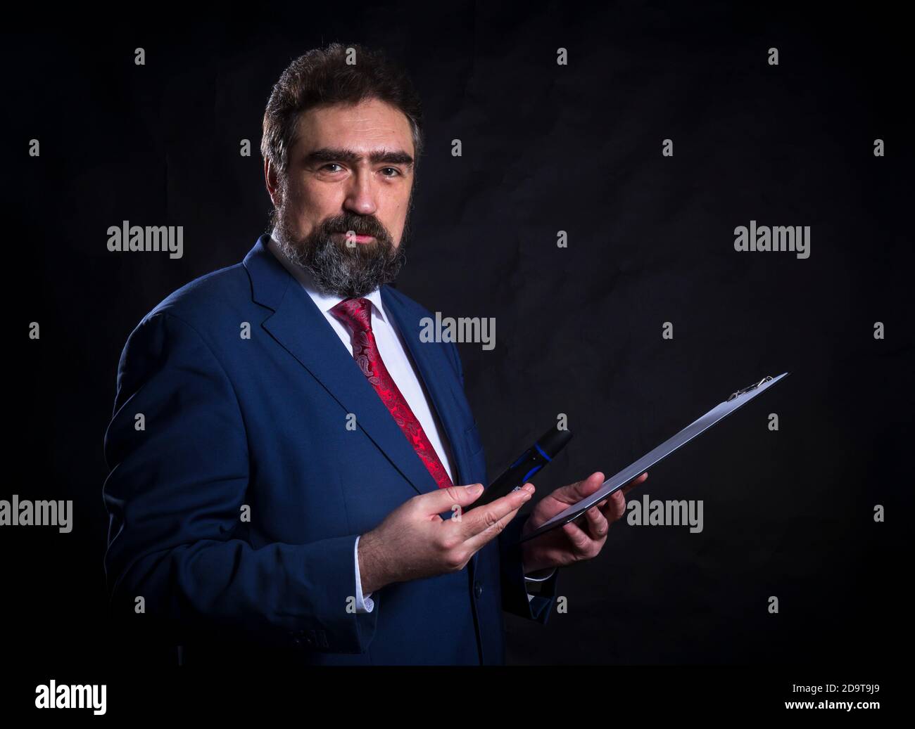 Mature businessman dressed in blue suit with red tie studio portrait ...