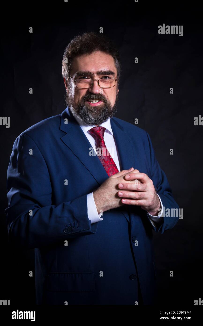 Mature businessman dressed in blue suit with red tie studio portrait ...