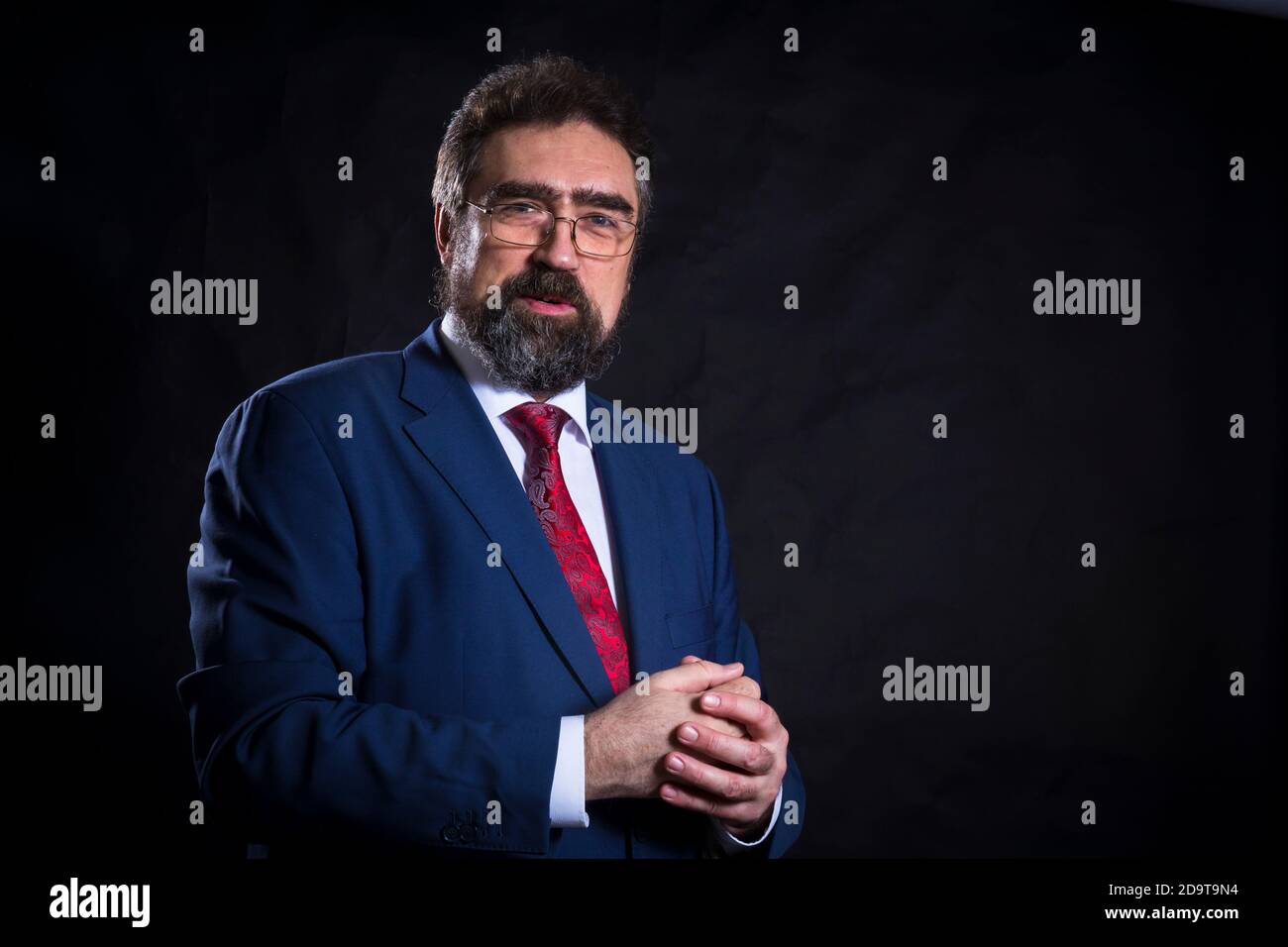 Mature businessman dressed in blue suit with red tie studio portrait ...