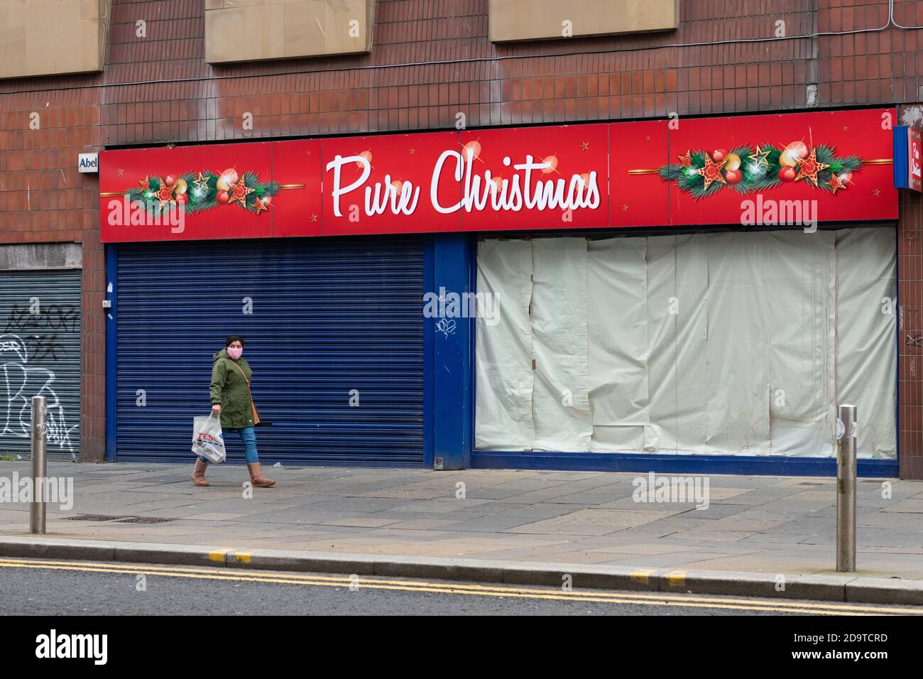 a member of the public walks past a closed 'pure christmas' shop in Glasgow, Scotland, UK during the coronavirus pandemic - November 2020 Stock Photo