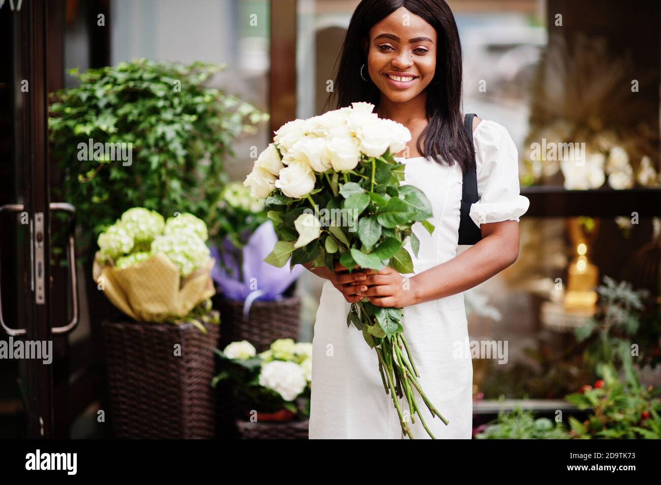 Beautiful african american girl holding bouquet of white roses flowers