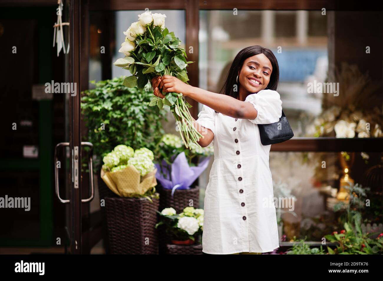 Beautiful african american girl holding bouquet of white roses flowers ...