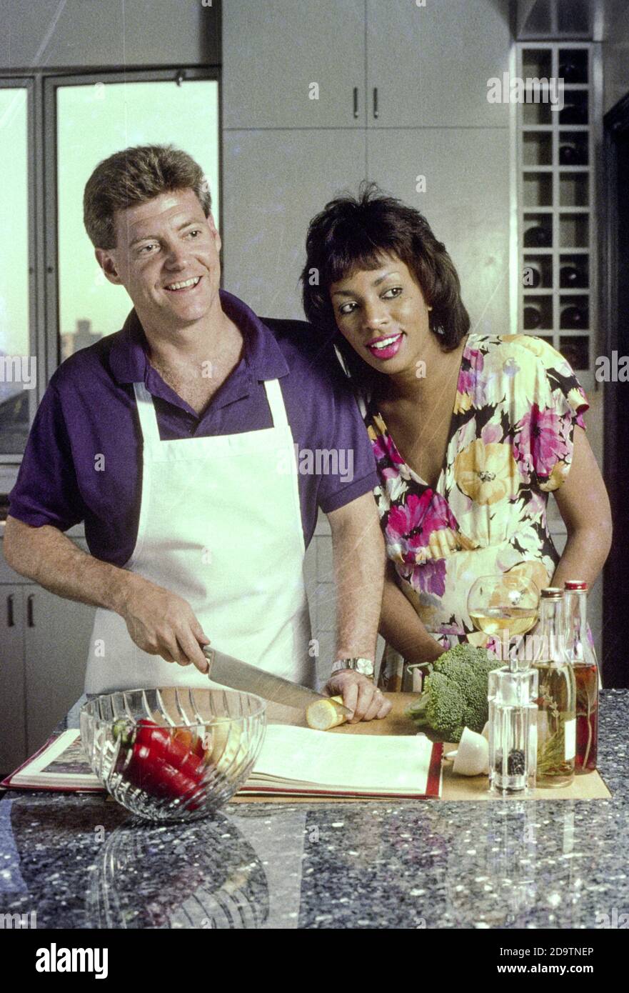 Mixed race couple enjoys cooking in a luxury upscale kitchen, USA  1980s Stock Photo