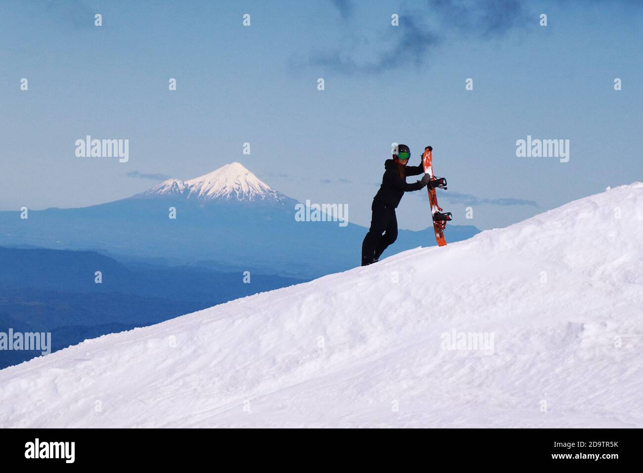 View of Mount Taranaki from Turoa Skifield, snowboarder in the background, winter season, New Zealand Stock Photo