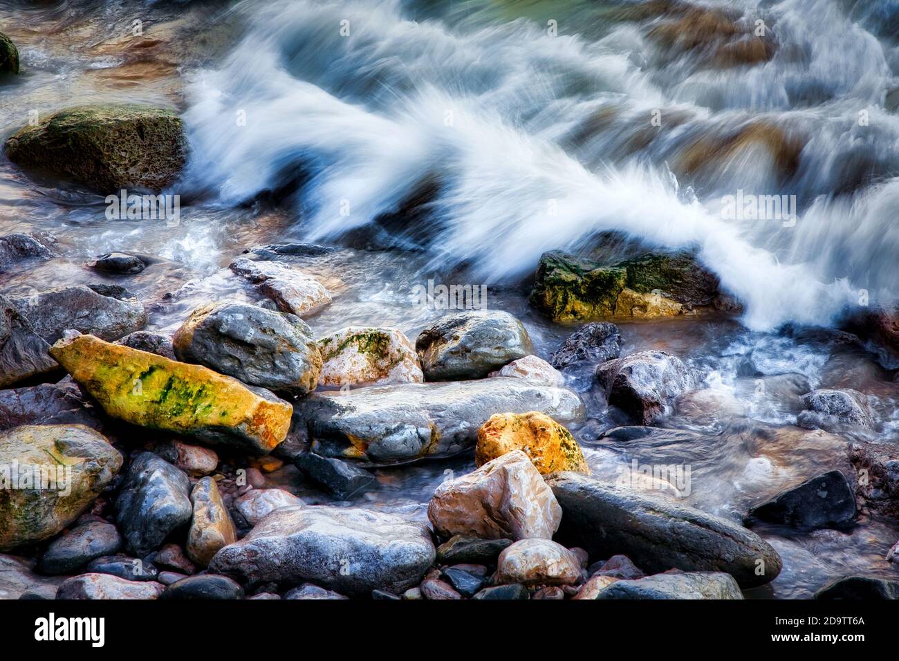 Tide against shore rocks Stock Photo - Alamy