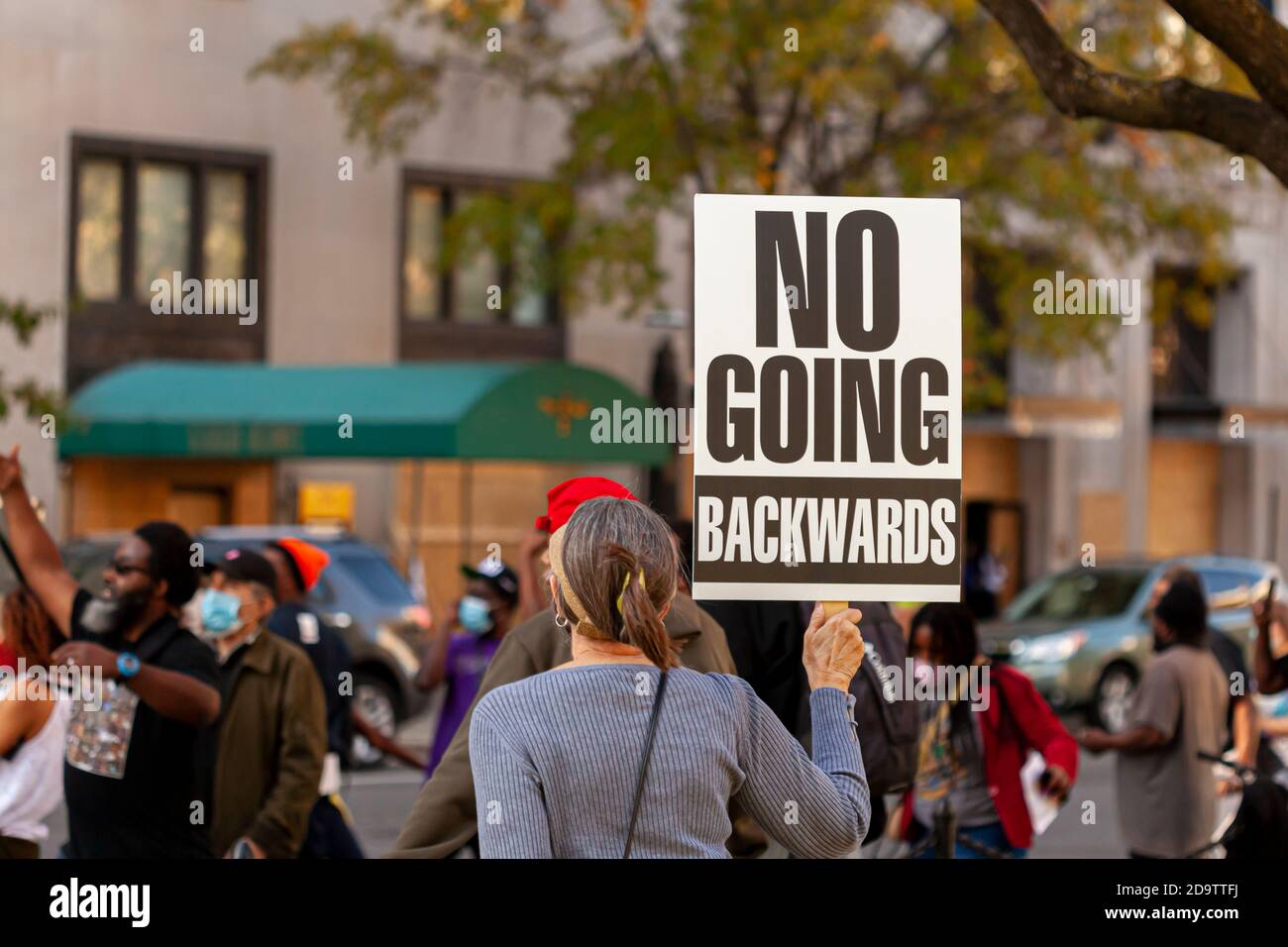 Washington DC, USA 11/06/2020: A woman protester is raising a banner that says: 'No Going Backwards'. Image taken at an Anti-Trump protest near White Stock Photo