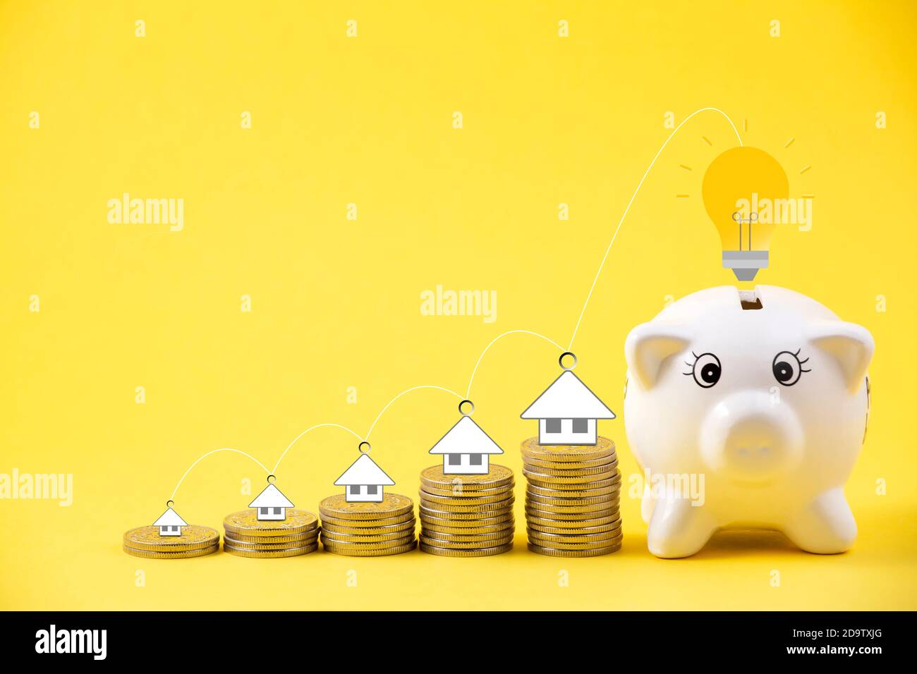 Happy Pink Piggy Bank and Light bulb in close-up and house icon on coins stack on yellow background, Saving ideas  and investment budget, Business sav Stock Photo