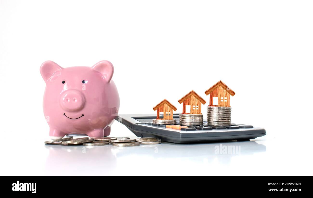Wooden house model that is on a money stack including pink piggy bank on white background, money-saving idea to buy a house. Stock Photo