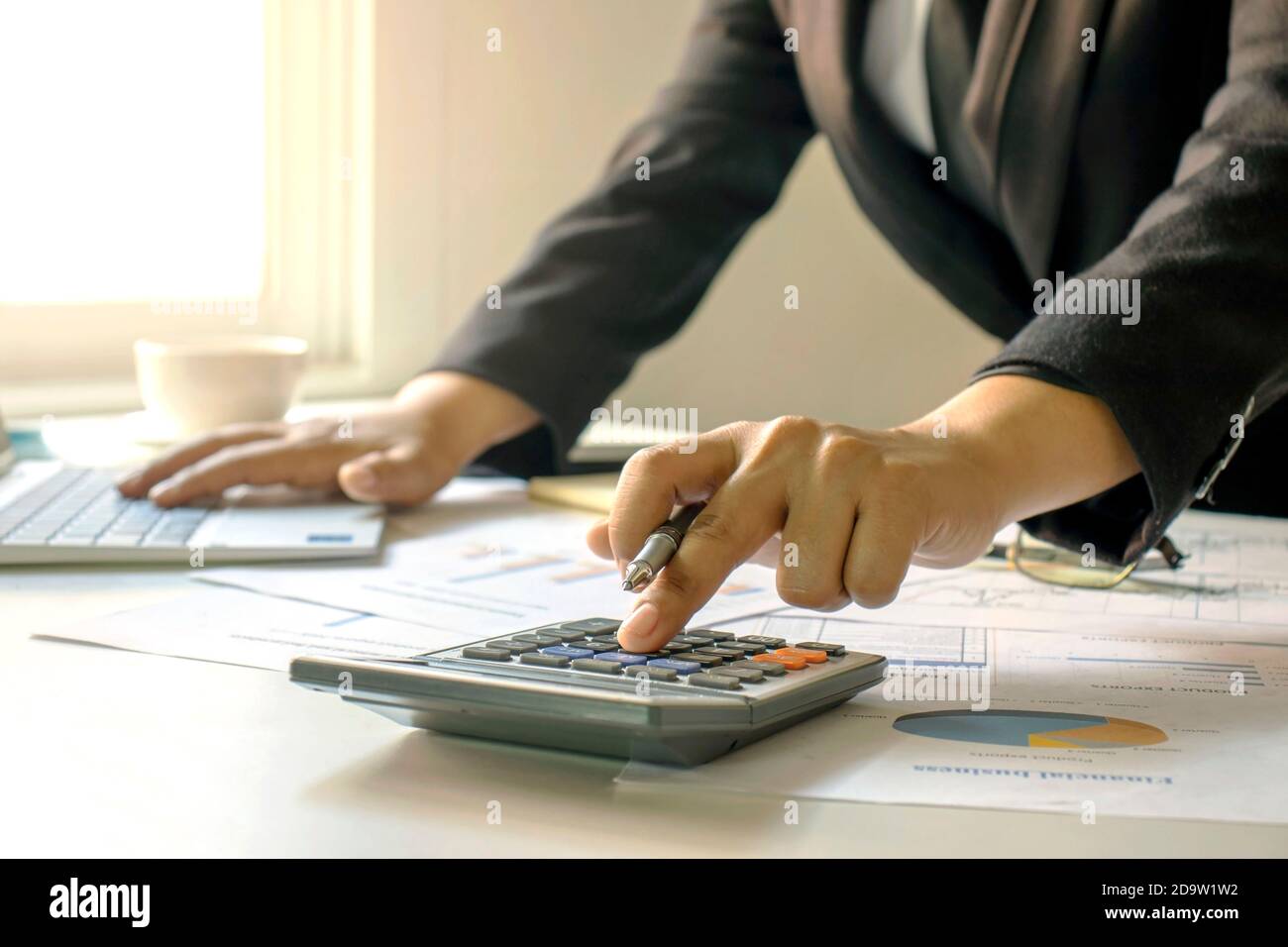 Businessmen are pressing a calculator to calculate the concept of business information on financial management and financing. Stock Photo