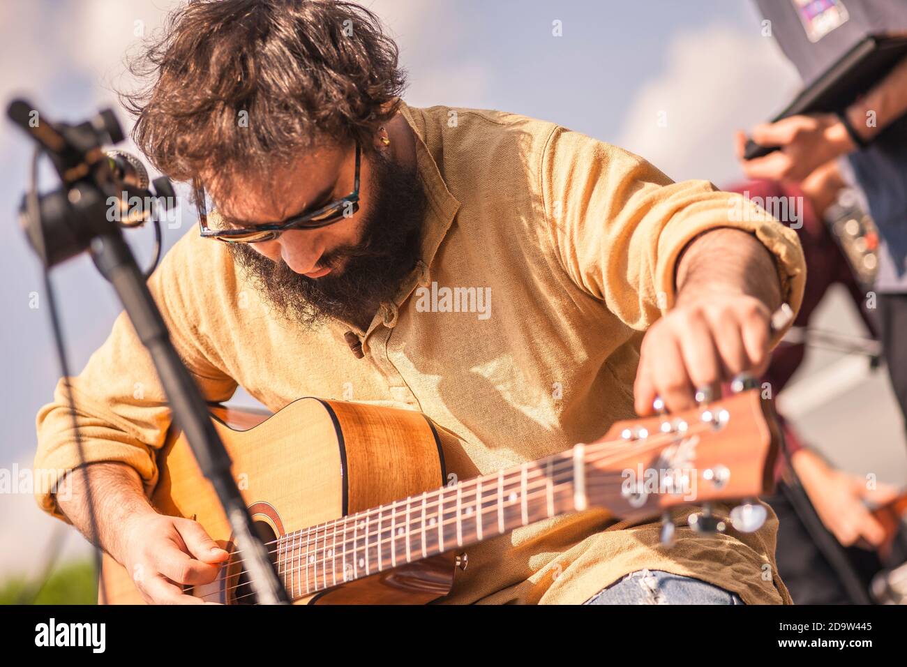 Guitarist tunes the guitar on stage where he will perform in a concert soon Stock Photo