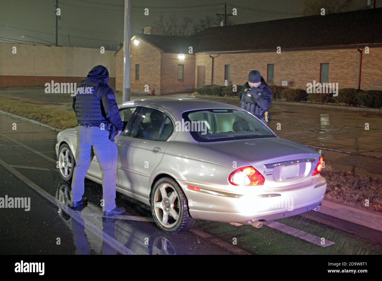 Detroit police officers speak to the driver of a car on a rainy night in Detroit, Michigan, USA Stock Photo