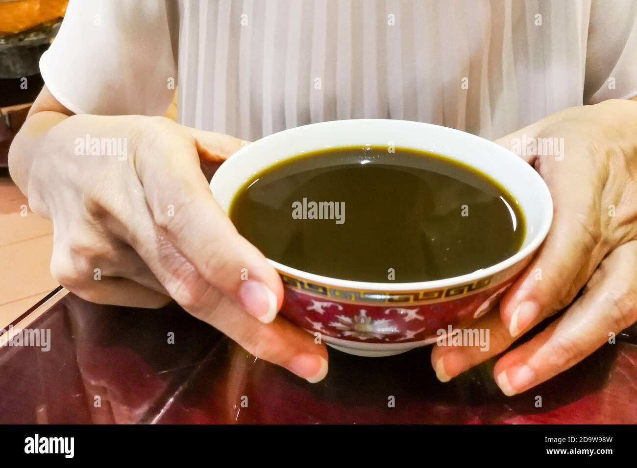 Person Holding Bowl Of Therapeutic Traditional Chinese Medicine Soup person-holding-bowl-of-therapeutic-traditional-chinese-medicine-soup