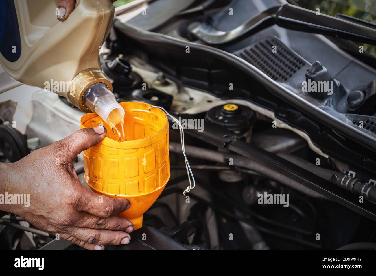 The car mechanic is adding oil to the engine, Automotive industry and