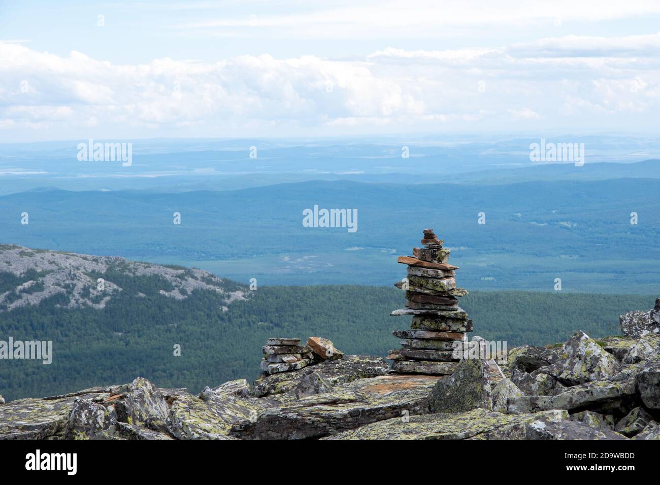 Stacked pyramid stones that mark a mountain trail, a landmark for hiking, against the backdrop of the Ural mountains, Russia. Stock Photo