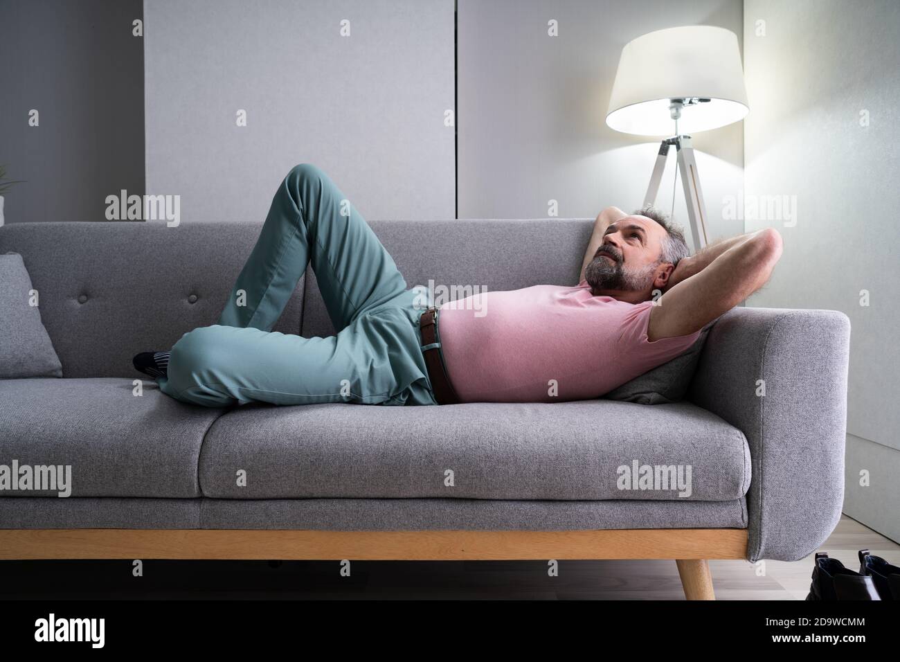 Senior Man Relaxing On Sofa In Living Room Stock Photo