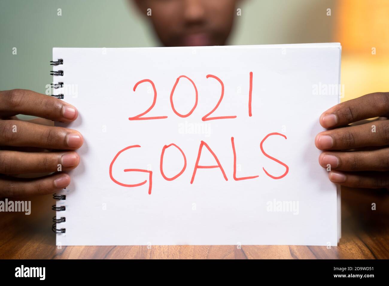 Man on table holding 2021 goals book in front of camera - concept of planning 2021 new year goals. Stock Photo