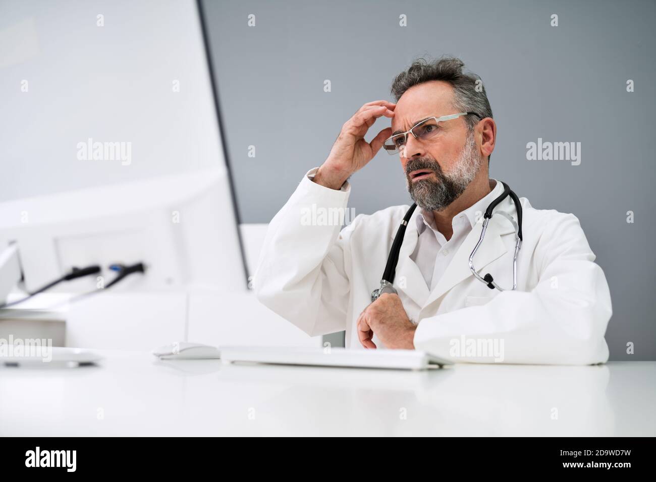 Old Sad Man Doctor Stress And Pain At Computer Stock Photo