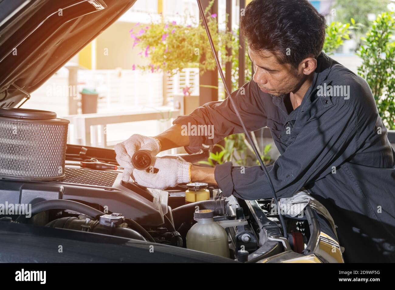 The technician is opening the oil tank of the car to check and repair