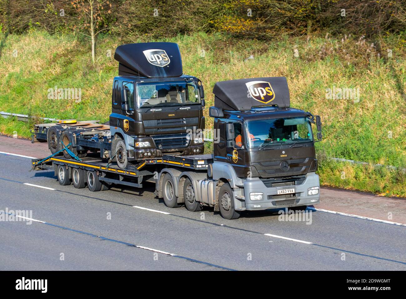 UPS, United Parcel Service an American multinational package delivery and supply chain postal management company; Motorway heavy bulk haulage lorry car transporter delivering trucks, haulage, carrier transportation, Mercedes Axor truck on low-loader, special cargo, Scania vehicle, UPS Package Car delivery, recover transport industry, parcel freight on the M61 at Manchester, UK Stock Photo