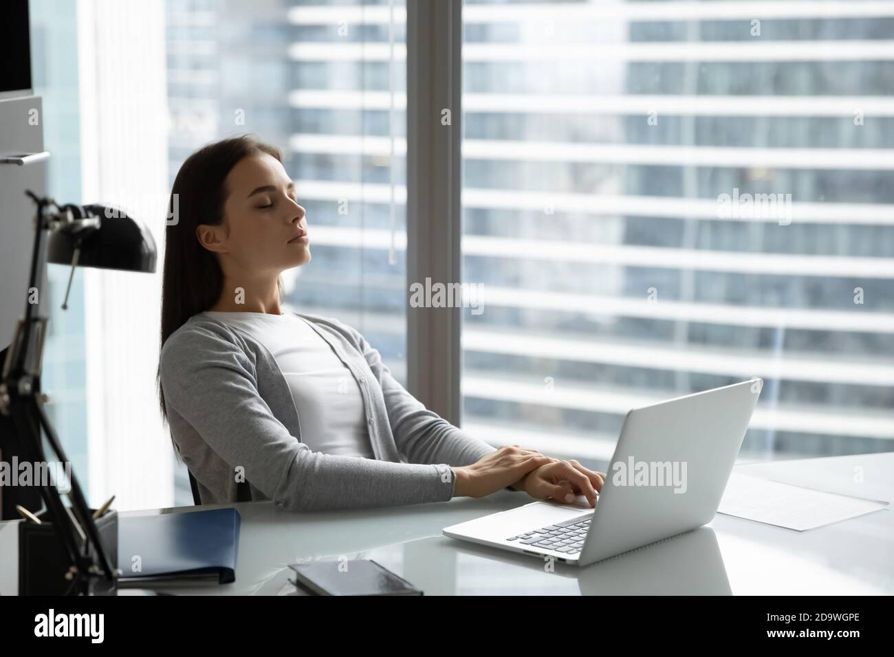 Peaceful woman employee with closed eyes leaning back on chair Stock Photo