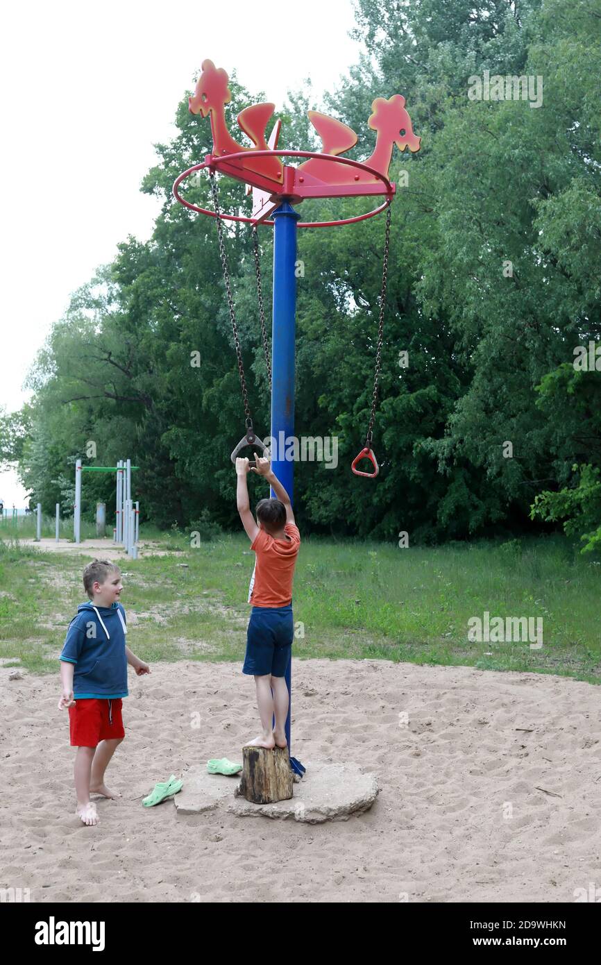 Boy on rotating rope swing around central pole in park Stock Photo - Alamy